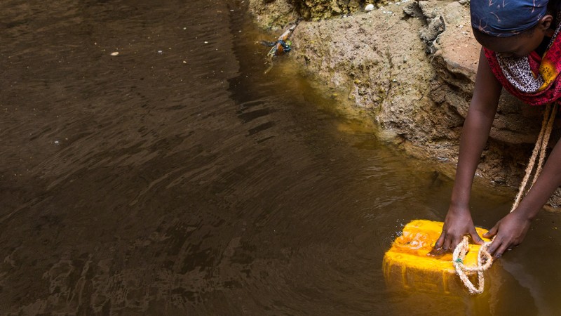 A lady collecting water in a jerry can